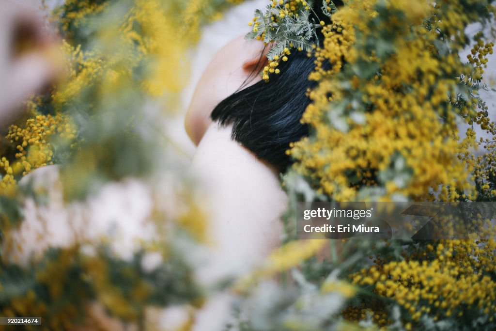 A woman surround by yellow flowers.