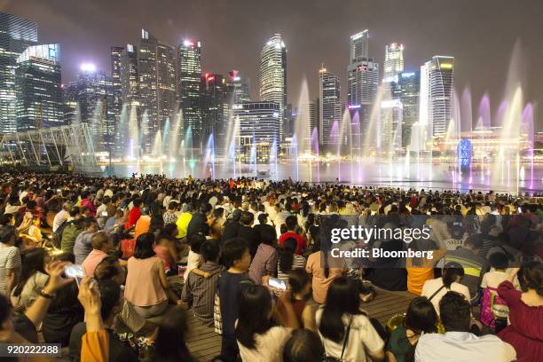 People take photographs as they watch the Spectra light and water show at the Marina Bay waterfront at night in Singapore, on Friday, Feb. 16, 2018....