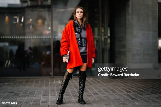 Landiana Cerciu wears a red coat, a red striped bag, a gray hoodie sweater, black leather thigh high boots, during London Fashion Week February 2018...