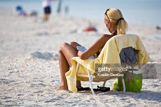 woman relaxes at beach doing puzzle - korsord bildbanksfoton och bilder
