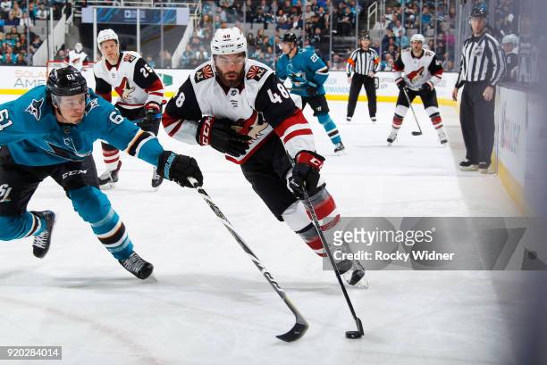 Jordan Martinook of the Arizona Coyotes skates with the puck against Justin Braun of the San Jose Sharks at SAP Center on February 13, 2018 in San...