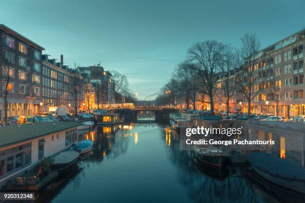 city lights and calm waters in the canals of amsterdam - boathouse fotografías e imágenes de stock