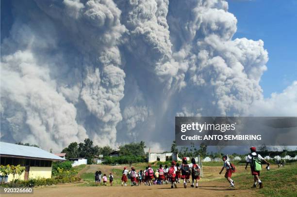 Indonesian schoolchildren walk together at Sipandak elementary school in Tiga Pancur village in Karo, North Sumatra on February 19 as thick volcanic...