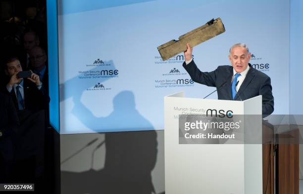 In this handout photo Israeli Prime Minister Benjamin Netanyahu holds up what he claims is a piece of an Iranian drone that was shot down after it...