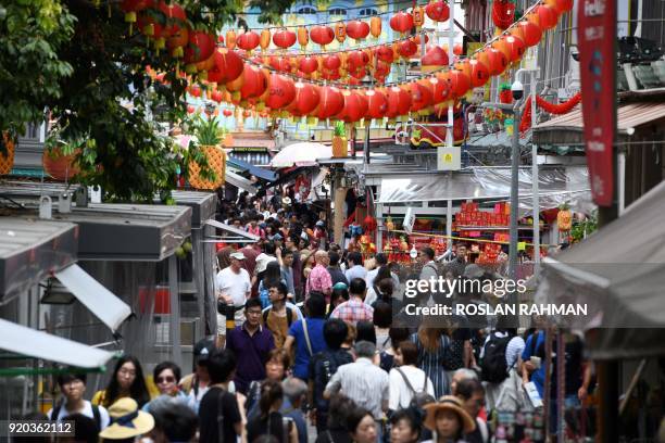 People walk along a crowded alleyway past stalls selling gifts and decorative items in the Chinatown district in Singapore on February 19, 2018....