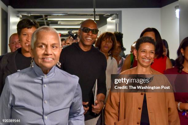 Comedian Dave Chappelle, C, passes through the hallways of Duke Ellington School of the Arts with DC mayor Muriel Bowser, L, and Peggy Cooper...