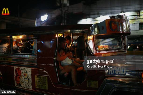Woman acting as the jeepney driver's conductor holds her child inside a jeepney in Manila, Philippines on Friday, February 3, 2018. The Jeepney has...