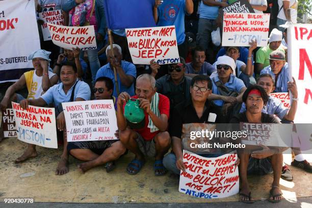 Jeepney drivers belonging to the activist jeepney driver group PISTON hold placards as they listen to a speech during a protest against the...