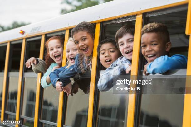 elementary school children looking out window of bus - school bus kids stock pictures, royalty-free photos & images