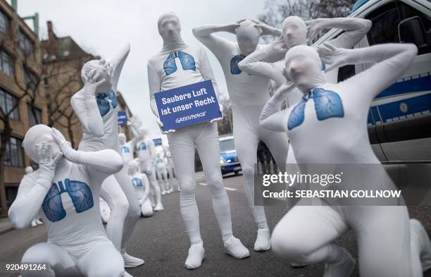 Greenpeace activists wear white morphsuits with lungs painted on them and hold a poster reading "We have the right to clean air" as they stage an...