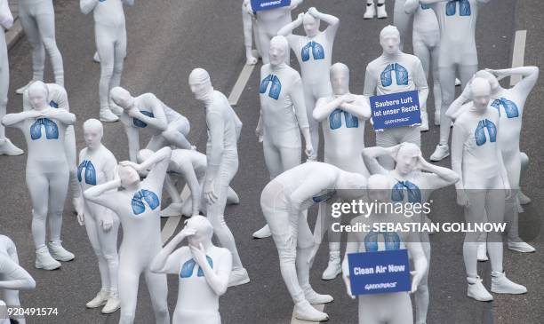 Greenpeace activists wear white morphsuits with lungs painted on them and hold a poster reading "We have the right to clean air" as they stage an...