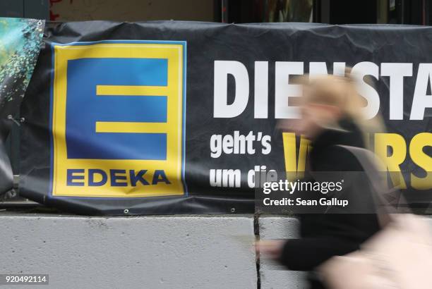 Young woman walks past a grocery store of German chain Edeka on February 19, 2018 in Berlin, Germany. According to media reports Agecore-Group, to...