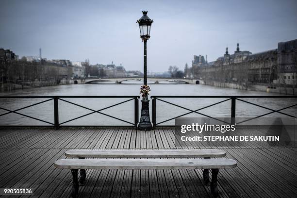 Lamp post with "love" padlocks attached to it along the Pont des Arts in central Paris is backdropped by the flooding Seine river backdrops on...