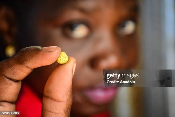 Woman holds raw gold with her index finger and thumb at a mine in Kakamega a western town of Kenya on February 16, 2018. Mine in Kakamega, which used...