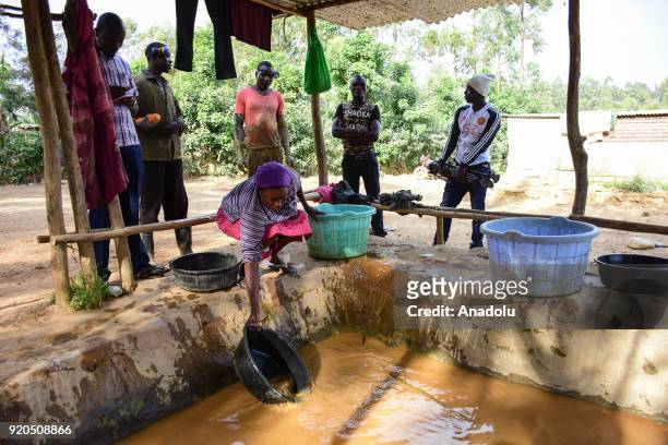 Workers, mostly women, wash rock pieces with water including mercury to find gold pieces blended in rock pieces in a washbowl at a mine in Kakamega a...