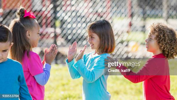 children playing outdoors on playground - clapping game stock pictures, royalty-free photos & images