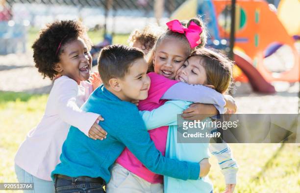 bambini che giocano all'aperto nel parco giochi, abbracciando - affettuoso foto e immagini stock