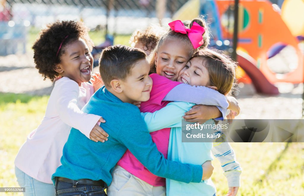 Children playing outdoors on playground, hugging