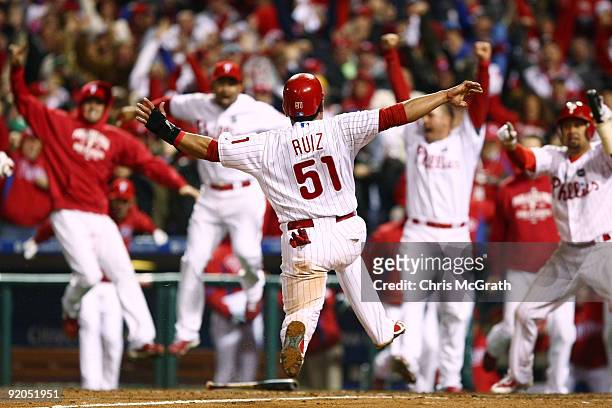 Carlos Ruiz of the Philadelphia Phillies celebrates with his teammates as he slides safely into home as he scores the winning run on a walkoff 2-run...