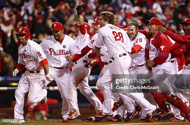 Shane Victorino, Miguel Cairo, Carlos Ruiz, Jayson Werth, Chase Utley of the Philadelphia Phillies celebrate as they run to greet Jimmy Rollins after...