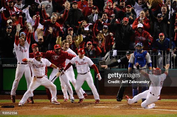 Carlos Ruiz of the Philadelphia Phillies celebrates with his teammates as he slides safely into home as he scores the winning run on a walkoff 2-run...