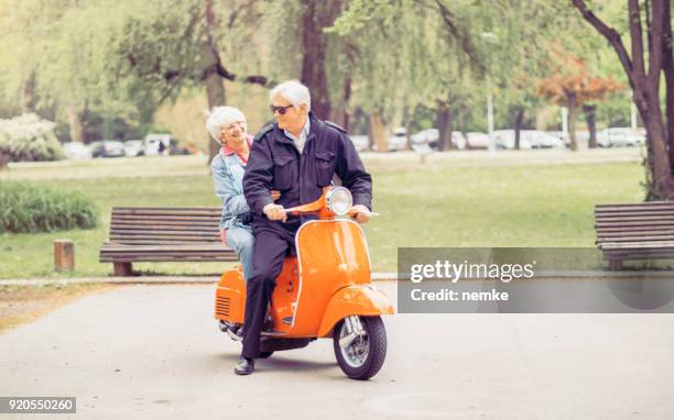 mujer mayor madura y hombre conduciendo una moto - city 70's fotografías e imágenes de stock