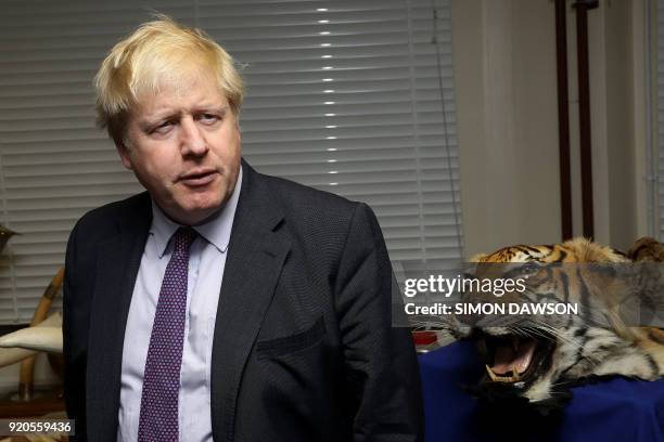 Britain's Foreign Secretary Boris Johnson stands next to a seized tiger skin rug as he visits a Metropolitan Police wildlife crime unit facility in...