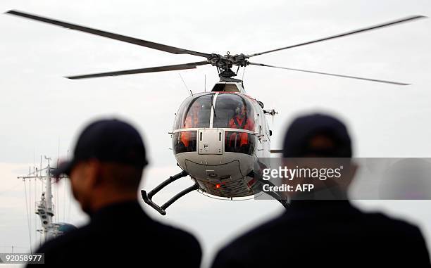 Members of the Philippine Coast Guard stand as one of their helicopters takes off at their headquarters in Manila on October 20 as teams deploy to...