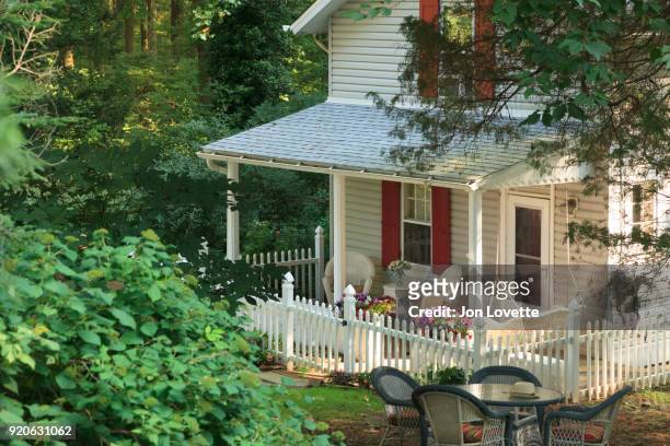 small home with porch surrounded by trees in summer - hollywoodschaukel stock-fotos und bilder