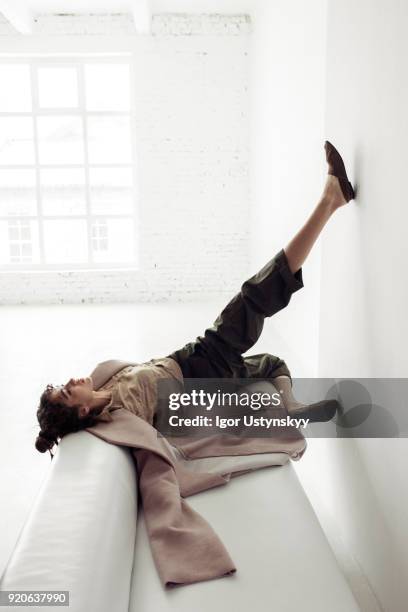 young woman lying on sofa with legs in air - piernas en el aire fotografías e imágenes de stock