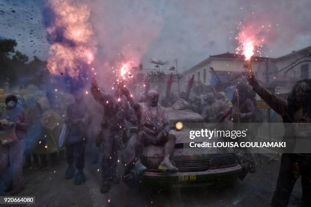 Revellers hold flares as they take part in the "flour war", during the celebration of "Ash Monday", a traditional festivity marking the end of the...