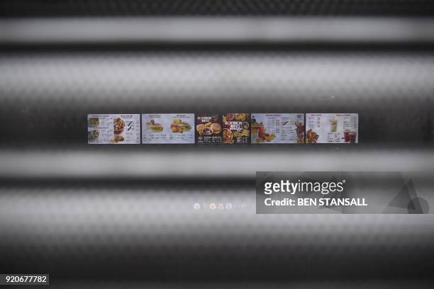 Sign seen through the shutters on a closed KFC fast food store in south London is closed on February 19, 2018 shows the menu. US fast food chain KFC...