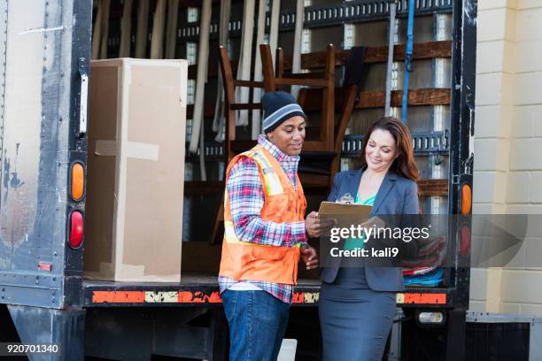 businesswoman receiving delivery, signing a clipboard - loader reading stock pictures, royalty-free photos & images