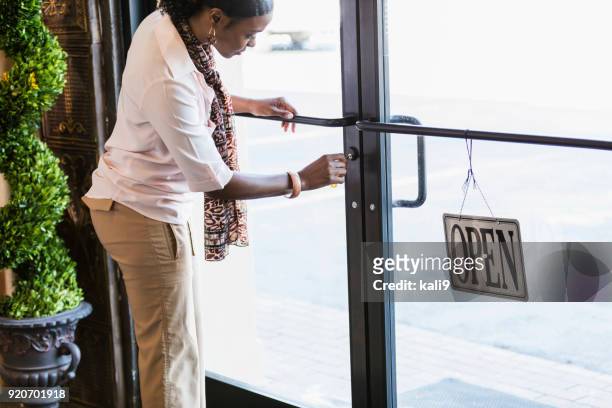 african-american woman opening store, unlocking the door - unlocking door stock pictures, royalty-free photos & images