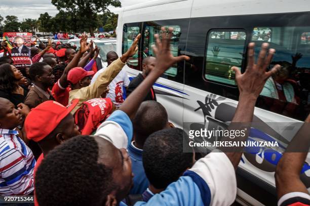 Mourners wave good bye as the hearse carrying Morgan Tsvangirai passes through supporters of the Movement for Democratic Change party gathered at...