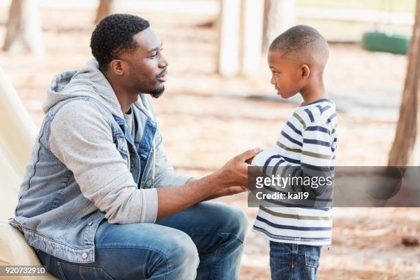 père de parler au petit garçon sur le terrain de jeu - père célibataire photos et images de collection