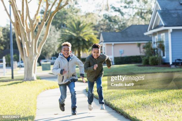 two boys running on sidewalk racing each other - race 8 stock pictures, royalty-free photos & images