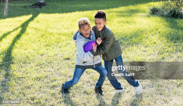 twee jongens voetballen in de achtertuin - rough housing stockfoto's en -beelden