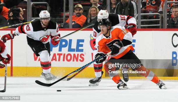 Travis Konecny of the Philadelphia Flyers skates the puck against Jimmy Hayes of the New Jersey Devils on February 13, 2018 at the Wells Fargo Center...