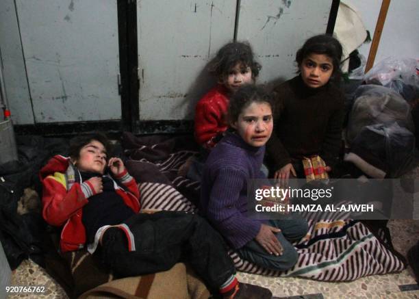 Graphic content / TOPSHOT - Syrian children cry at a make-shift hospital in Douma following air strikes on the Syrian village of Mesraba in the...