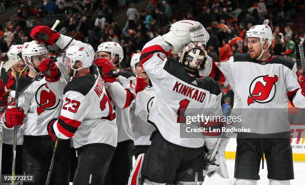 Jimmy Hayes and Keith Kinkaid of the New Jersey Devils celebrate with teammates after defeating the Philadelphia Flyers 5-4 in a shootout on February...