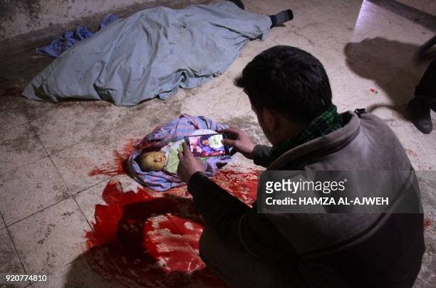 Graphic content / A Syrian man takes a picture of the body of a baby at a make-shift morgue in Douma after they were killed in air strikes on the...