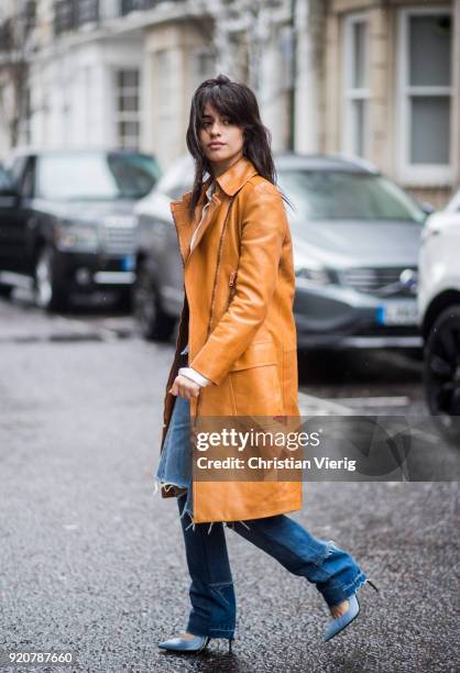 Camila Cabello wearing ripped denim jeans, pointed shoes, brown orange coat seen during London Fashion Week February 2018 on February 19, 2018 in...