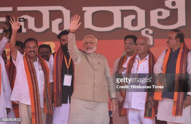 Prime Minister Narendra Modi waves as BJP state president and Chief Minister candidate Yeddyurappa looks on during a political rally at Maharaja...