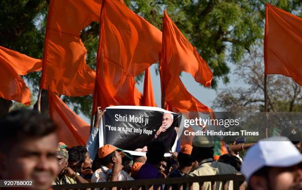 Supporters of BJP showing poster during a political rally of the Prime Minister Narendra Modi ahead of state Assembly election at Maharaja Ground on...