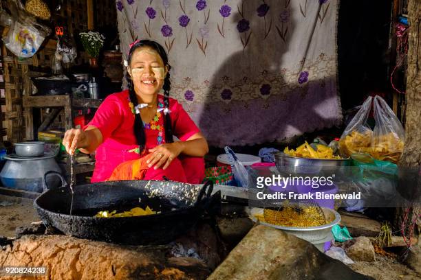Woman is cooking snacks on open fire in the street market of town.