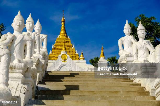 White Buddha statues are flanking the stairs up to the golden Settawya Paya Pagoda in Mingun.