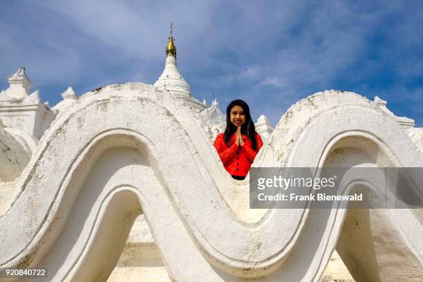 Young woman is praying inside the white building structures of the Hsinbyume Paya Pagoda in Mingun.