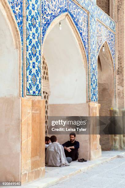 Men sitting under an arch in the Masjed-e Jame or Friday Mosque in Esfahan, Iran.