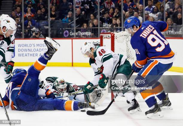 Devan Dubnyk and Jared Spurgeon of the Minnesota Wild desperately defend the net against John Tavares and Anders Lee of the New York Islanders during...